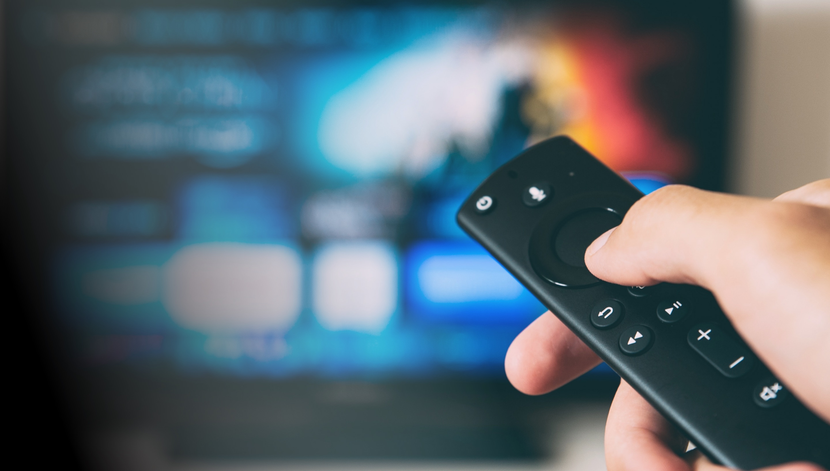 A person selecting streaming with a remote directed toward a television